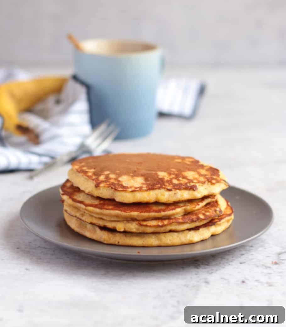 Four large pancakes on a grey plate behind a white background.