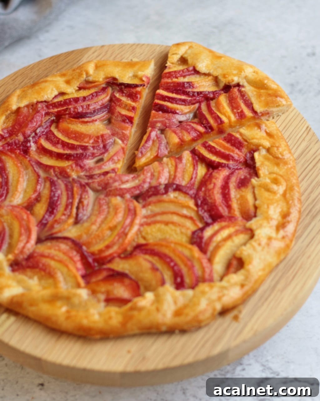 Almond Peach Galette with a slice cut out, ready to be served, on a wooden surface.