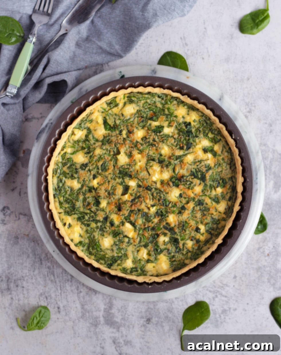 An uncooked Spinach and Feta Quiche in a tart pan, ready to be baked, showcasing the pastry crust and filling ingredients.