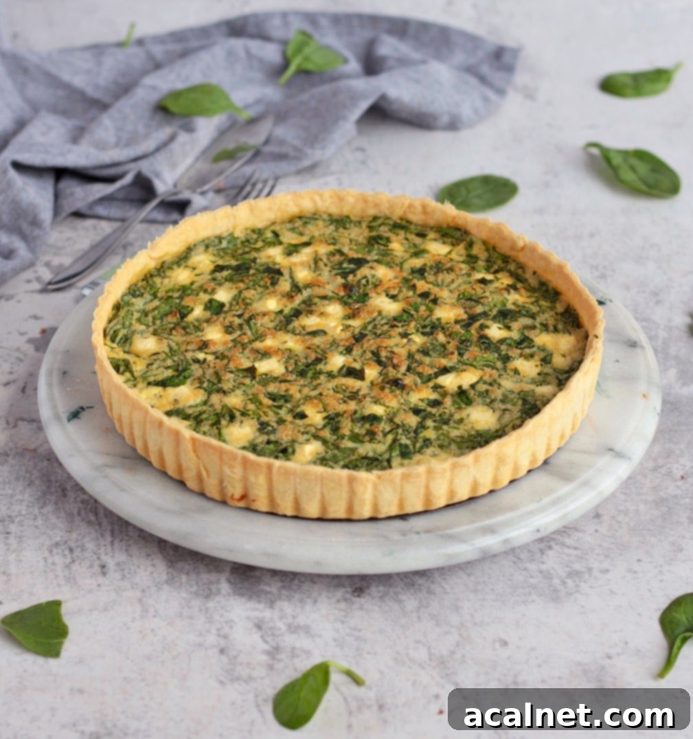 A freshly baked Spinach and Feta Quiche on a rustic marbled board, ready to be sliced and served.