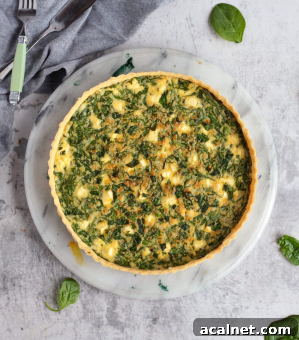 A whole Spinach and Feta Quiche presented beautifully on a marble board, ready to be served.