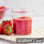 Strawberry Coulis in a Glass Jar surrounded by fresh strawberries