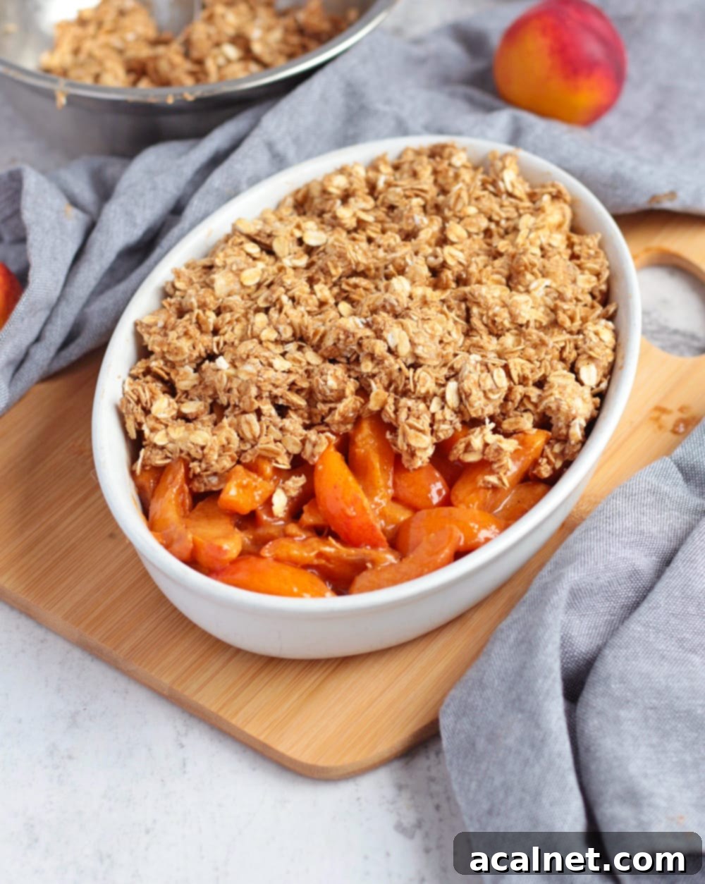 Apricot filling in a ceramic dish half covered by the crumble topping