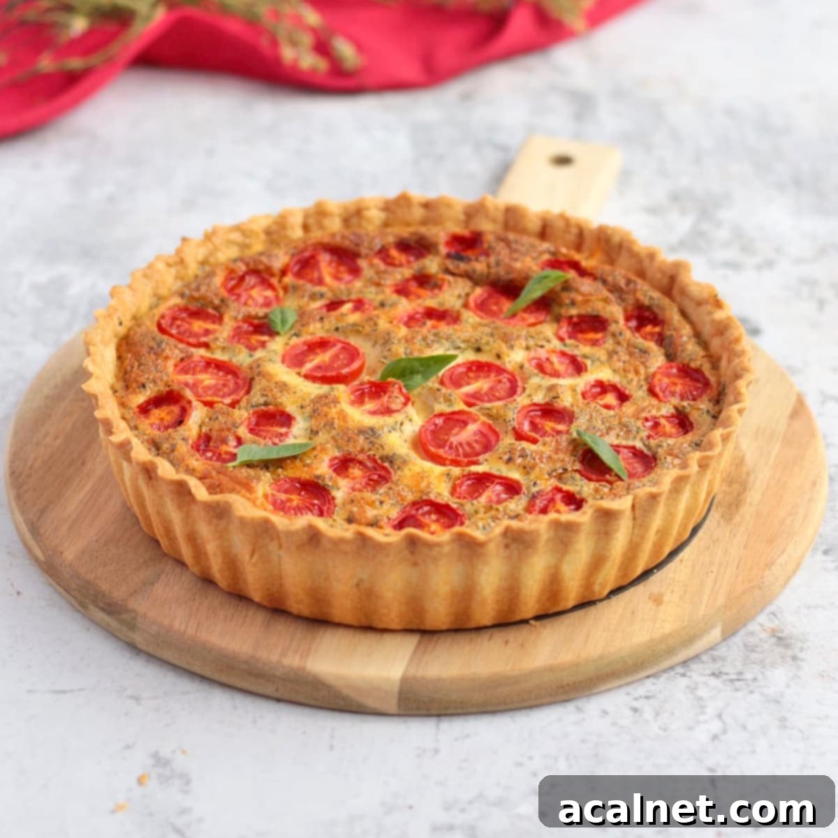 Cheese Quiche with Tomato on a serving board, garnished with fresh basil leaves.
