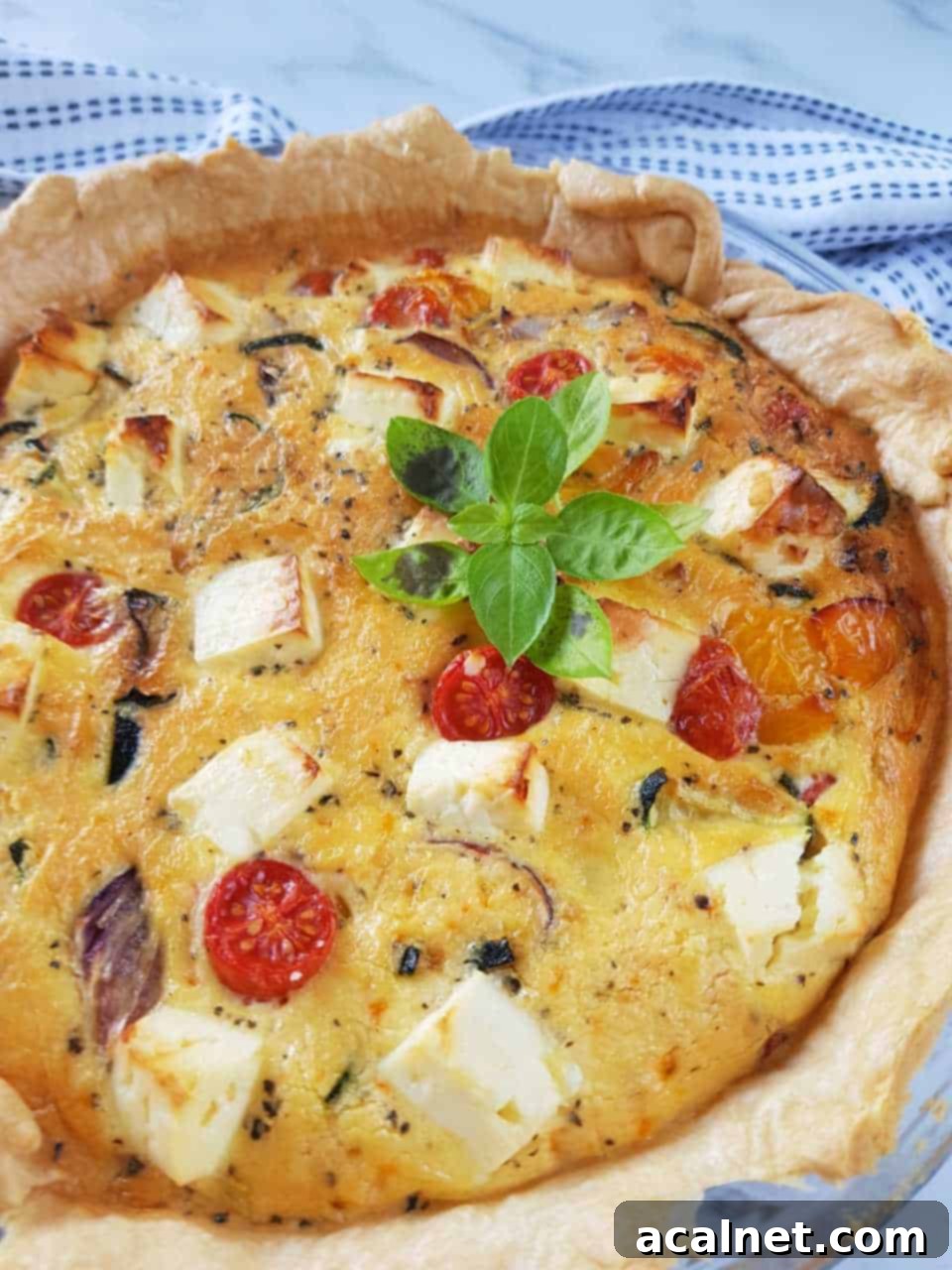 Quiche with roasted vegetables and feta cheese, displaying vibrant colors and a rustic, inviting appeal.