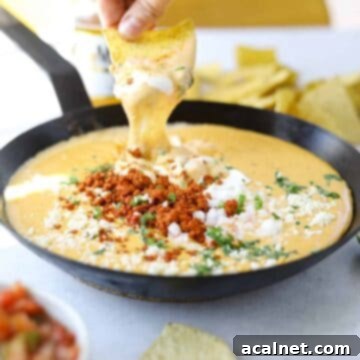 Creamy Choriqueso dip with chorizo in a cast iron skillet, served with tortilla chips.