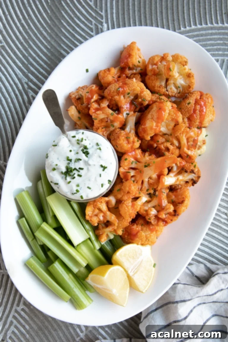Baked Buffalo Cauliflower  florets in a bowl with a side of dipping sauce.