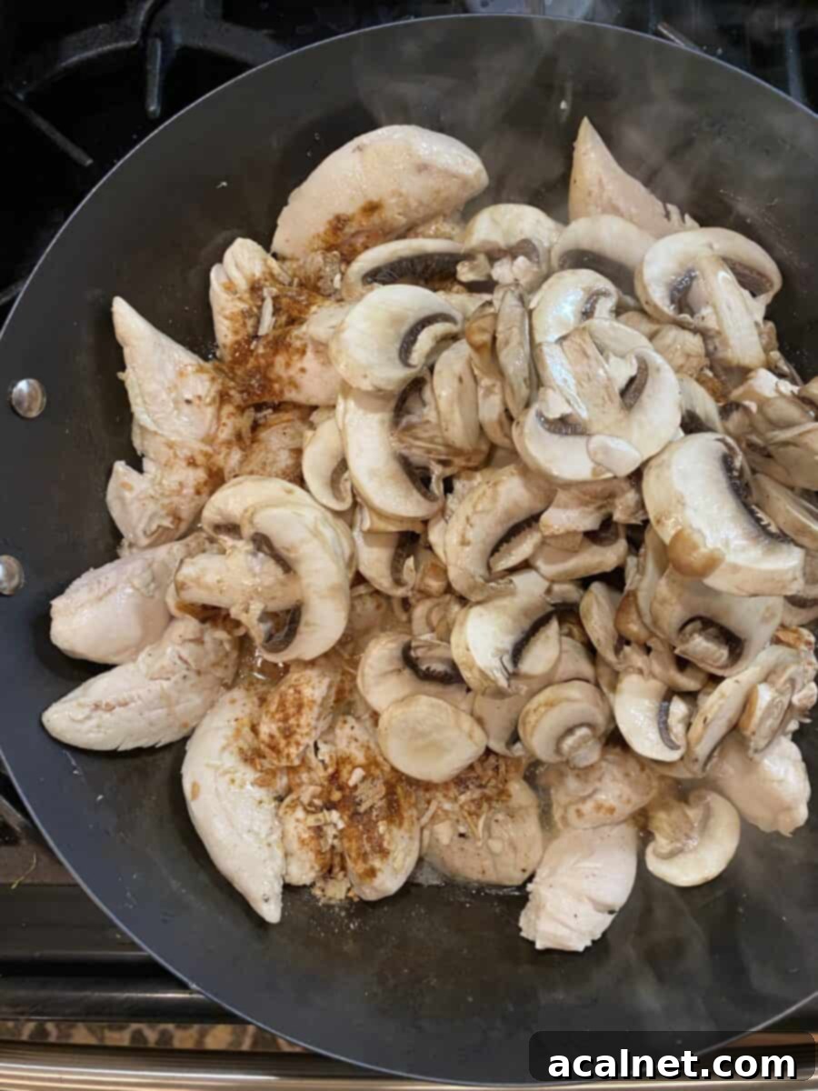 Creamy Chicken and Mushroom Stroganoff 10 Sliced fresh mushrooms placed on top of cooked chicken and seasoning in a skillet, ready to be stirred in.