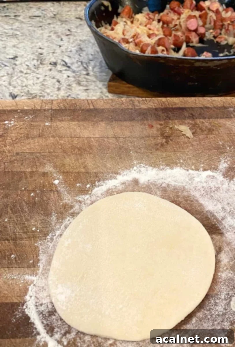 Dinner roll dough rolled into a perfect circle, with a skillet of filling nearby, ready for assembly.