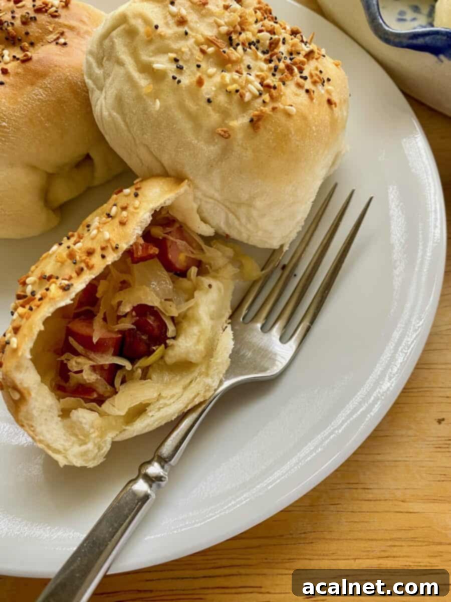 Little Smokie and sauerkraut filling in a halved portion of a dinner roll, ready to be enjoyed.