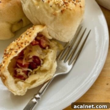 Little Smokie and sauerkraut filling in a halved portion of a dinner roll, showcasing the delicious filling.
