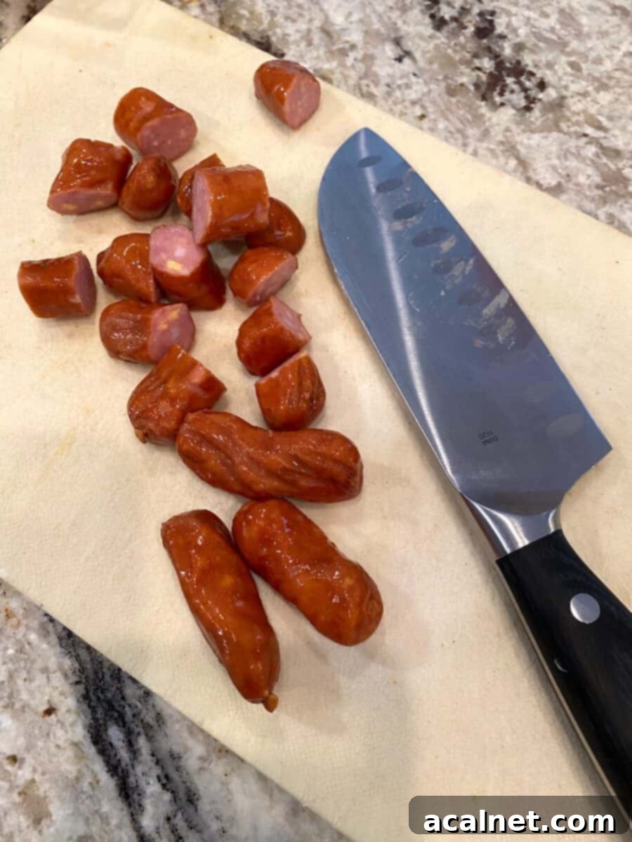Diced little smokies on a small cutting board with a knife beside them, ready for the skillet.