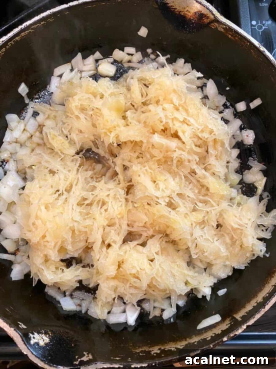 Diced onions and sauerkraut gently cooking in a cast iron skillet on the stovetop.