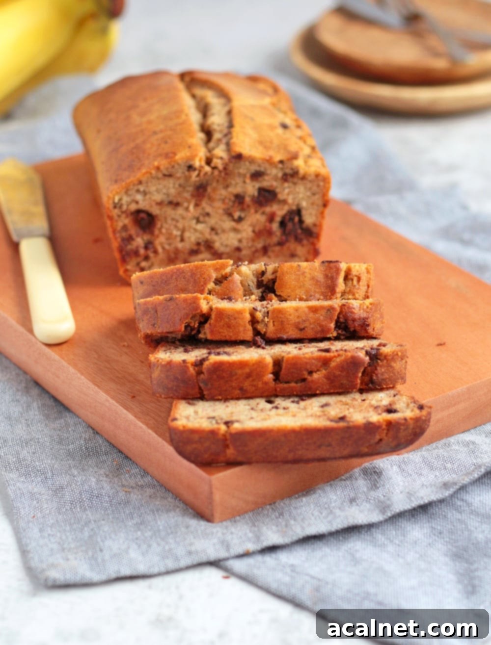 Close-up of four slices of incredibly moist chocolate chip banana bread on a wooden board.