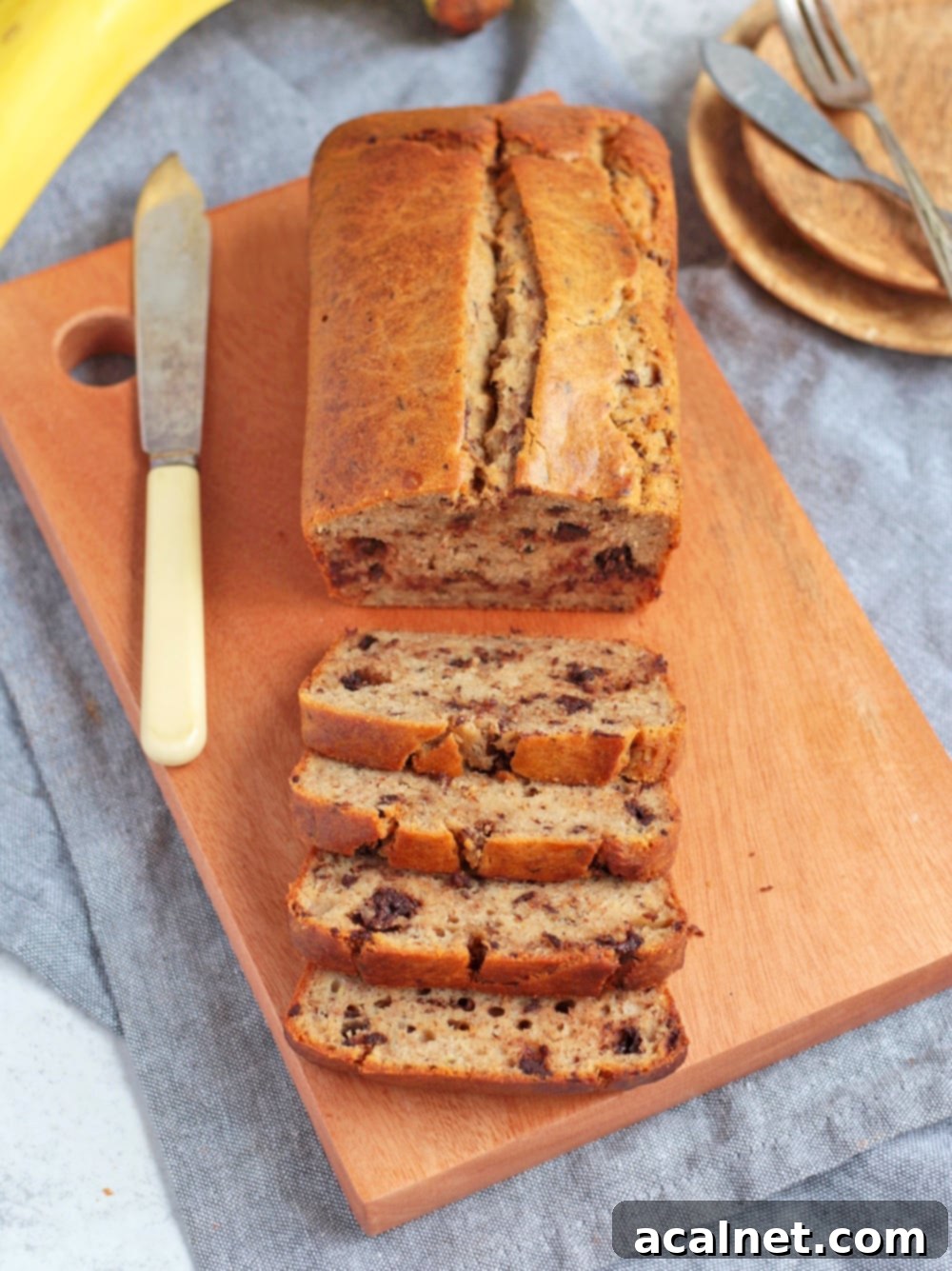 Golden-brown sweet bread on a wooden board, with a knife ready for slicing.