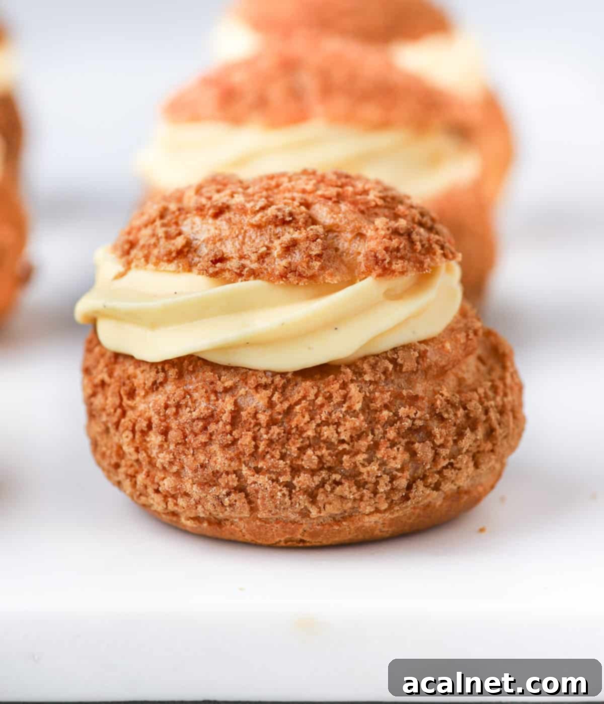 One choux filled with vanilla cream on a white surface.