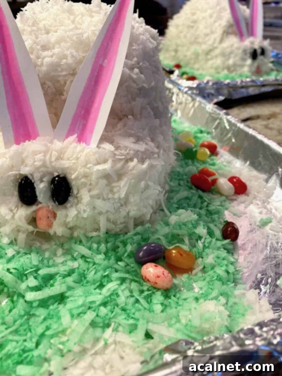 Two baked bunny cakes on baking sheets with coconut.