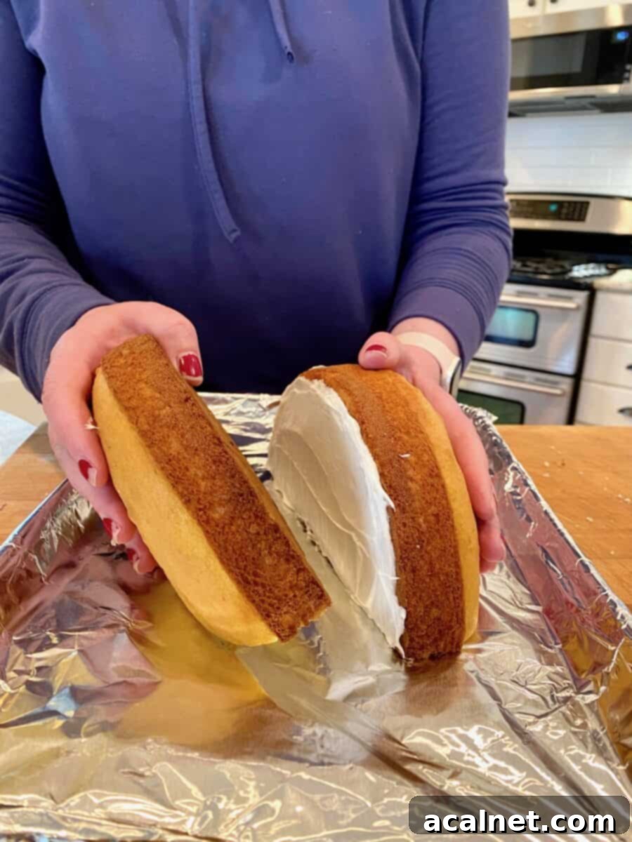Frosting added onto two halves of round cakes. 