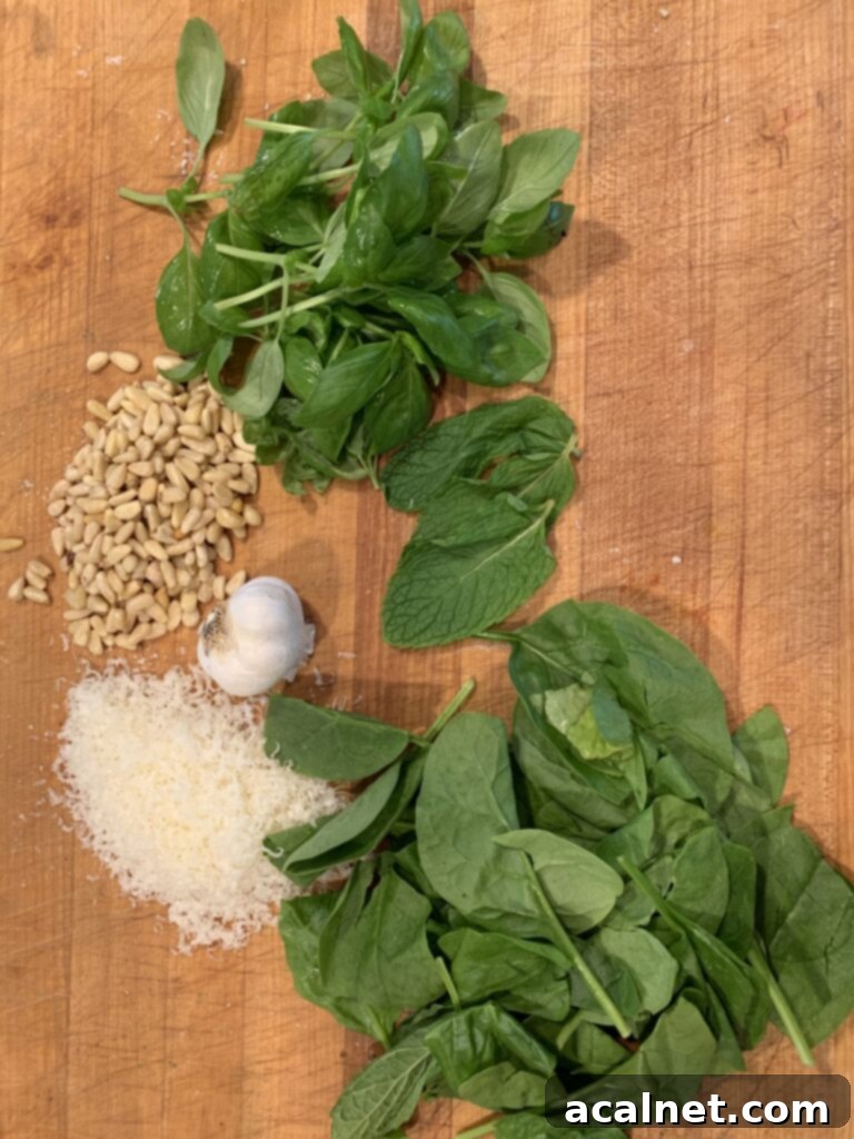 Basil, mint and spinach with garlic and pine nuts and parmesan on a cutting board. 