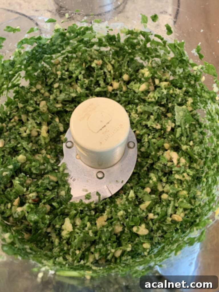 Basil, spinach and all recipe ingredients in a food processor bowl 