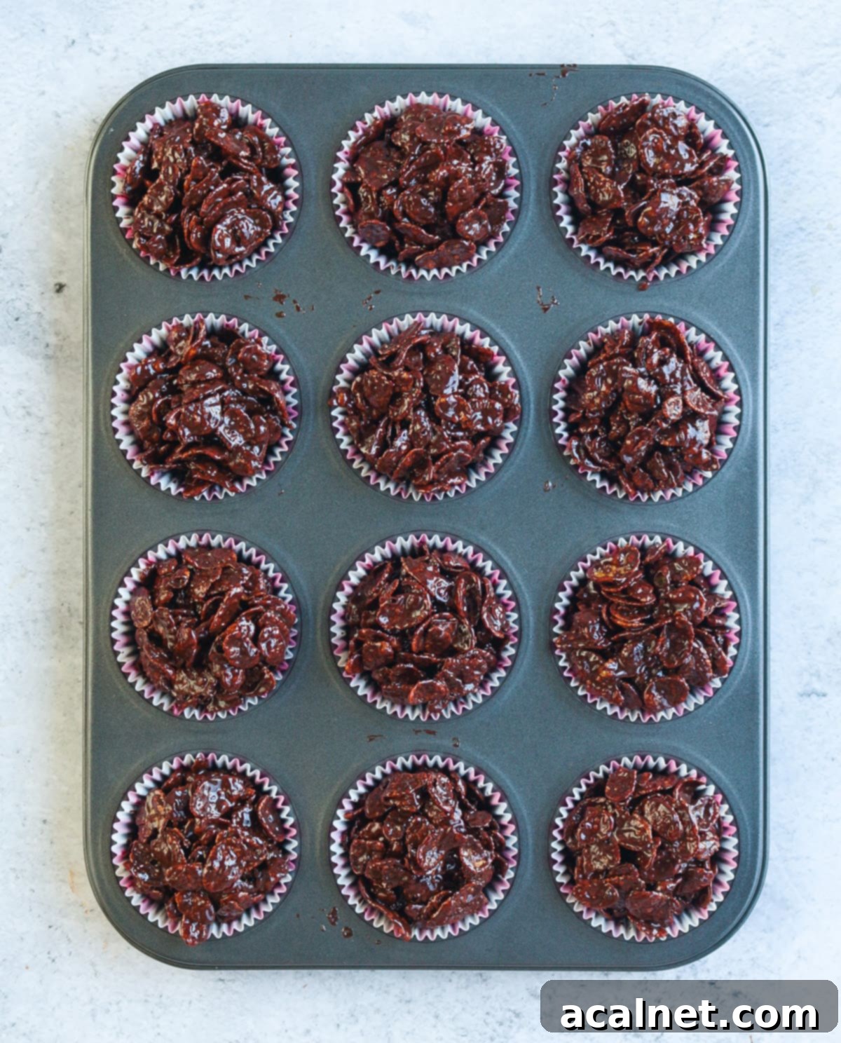 Process Shot: placing the chocolate cornflake cake batter into pink and white muffin liners in a muffin pan.