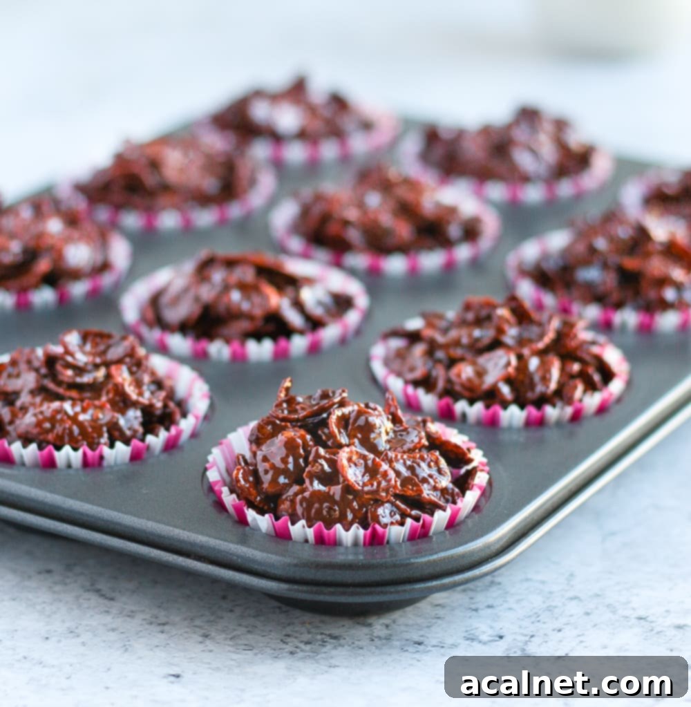 Small chocolate cornflake cakes presented in pink and white muffin liners in a muffin pan, ready to serve.
