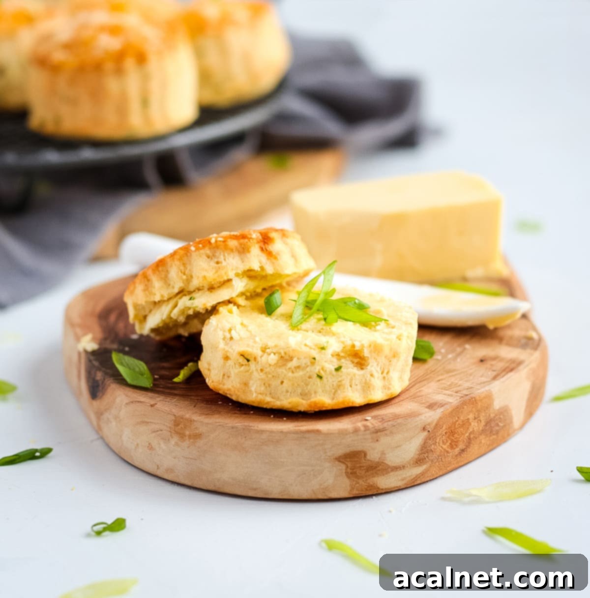 One scone on a wooden tray sliced in half and topped with butter