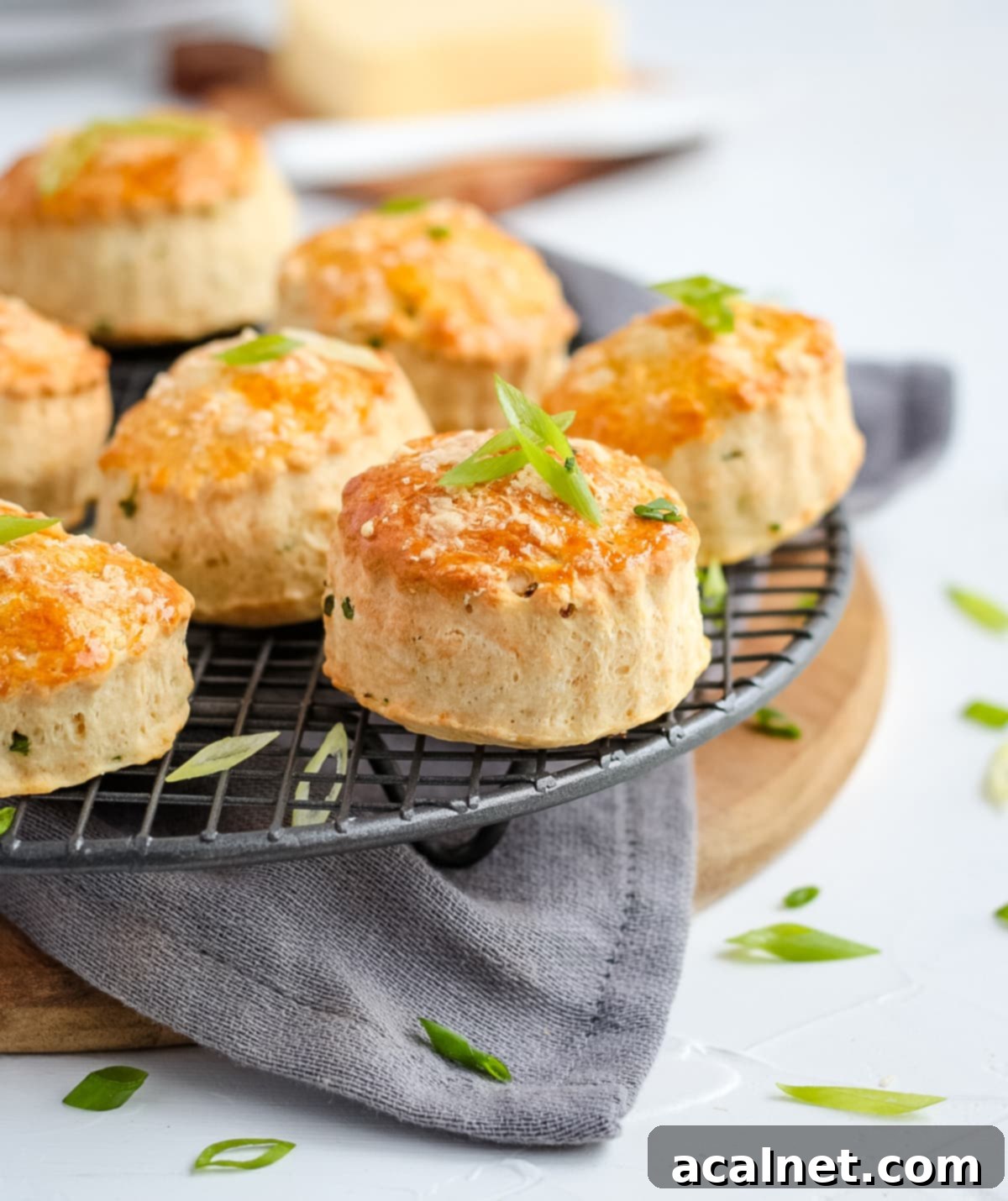 Scones on a round cooling rack over a grey napkin and wooden board