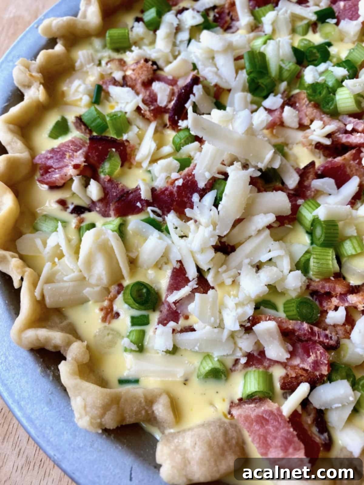 Unbaked quiche with vegetables and cheese sprinkled on top, ready to go into the oven.
