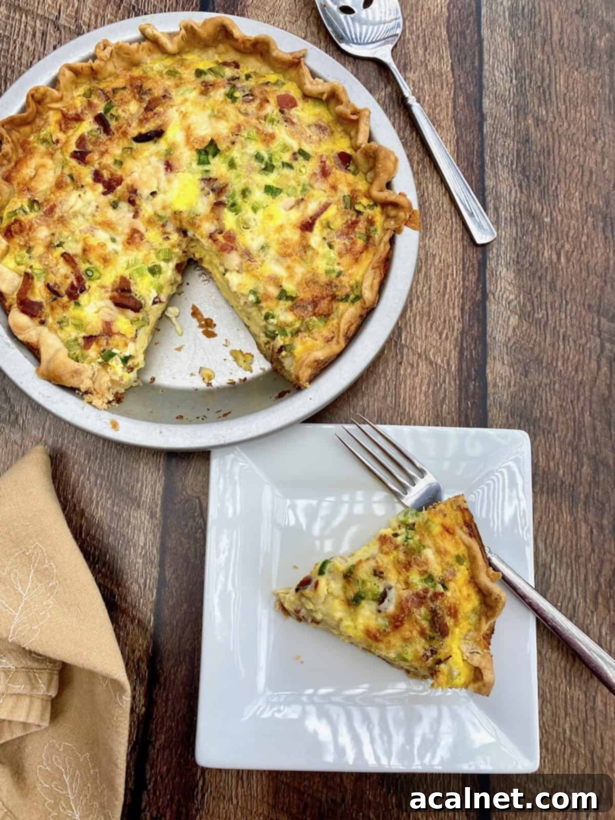 A wedge of Cougar Gold cheese on a small plate next to a dish of quiche, emphasizing the cheese used in the recipe.