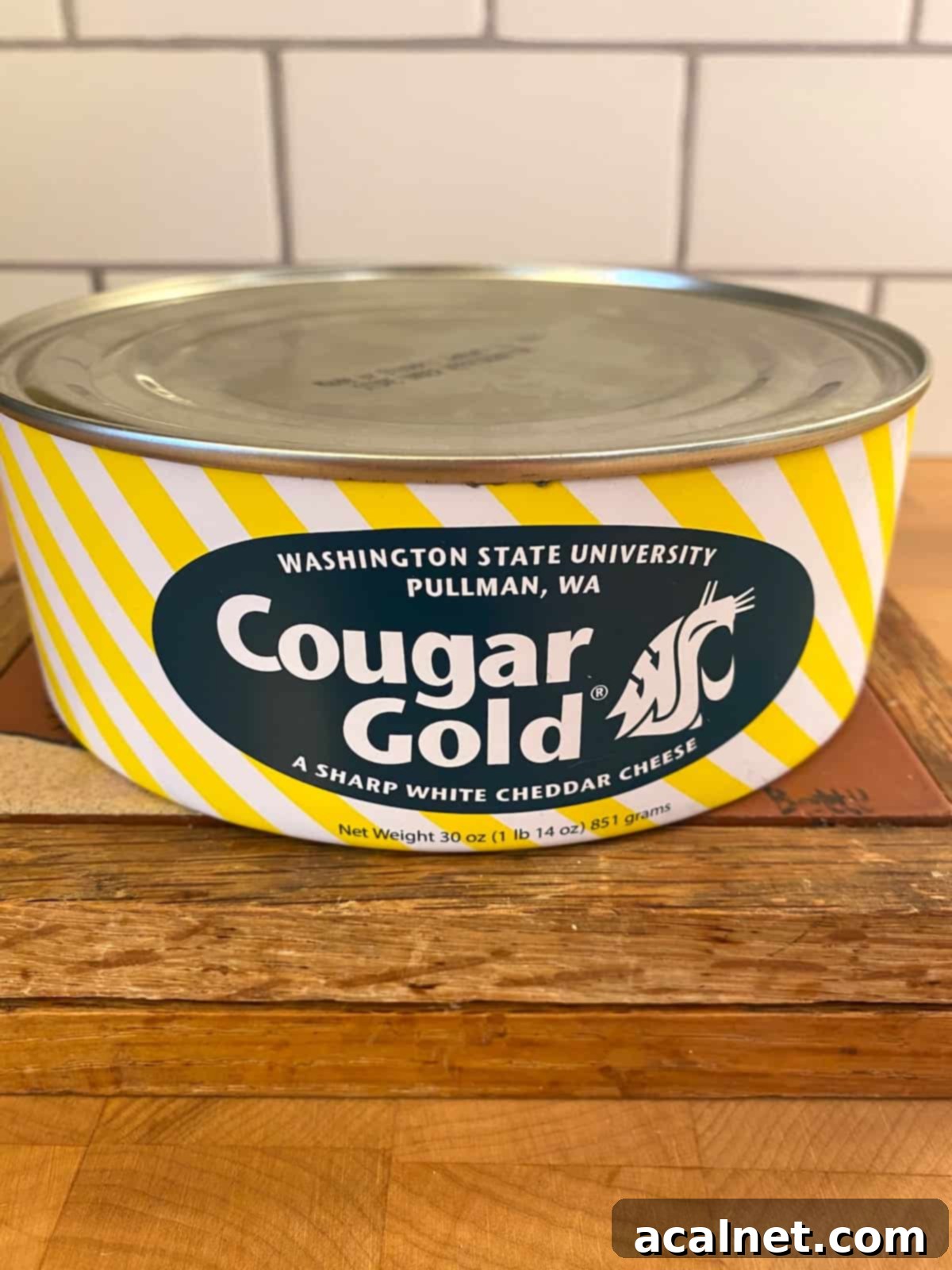 One can of Cougar Gold cheese on a cutting board, highlighting its unique packaging.