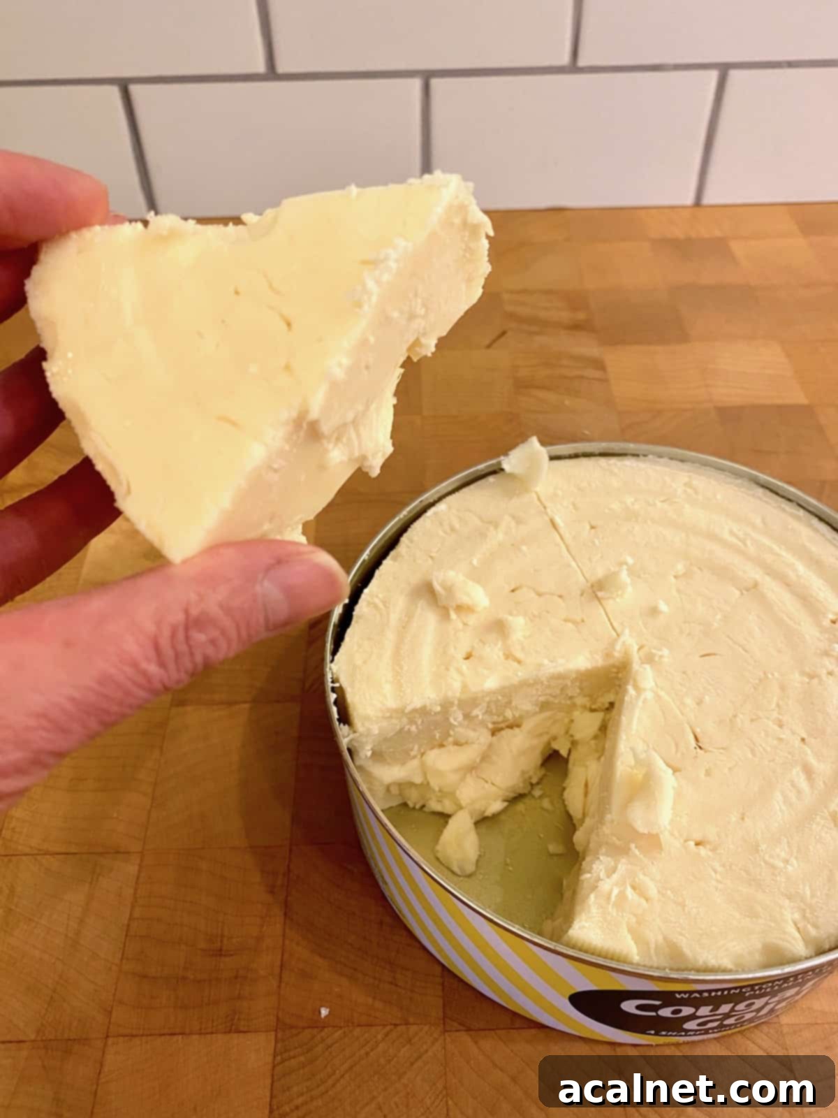 A wedge of white sharp cheddar cheese, showcasing its rich texture.