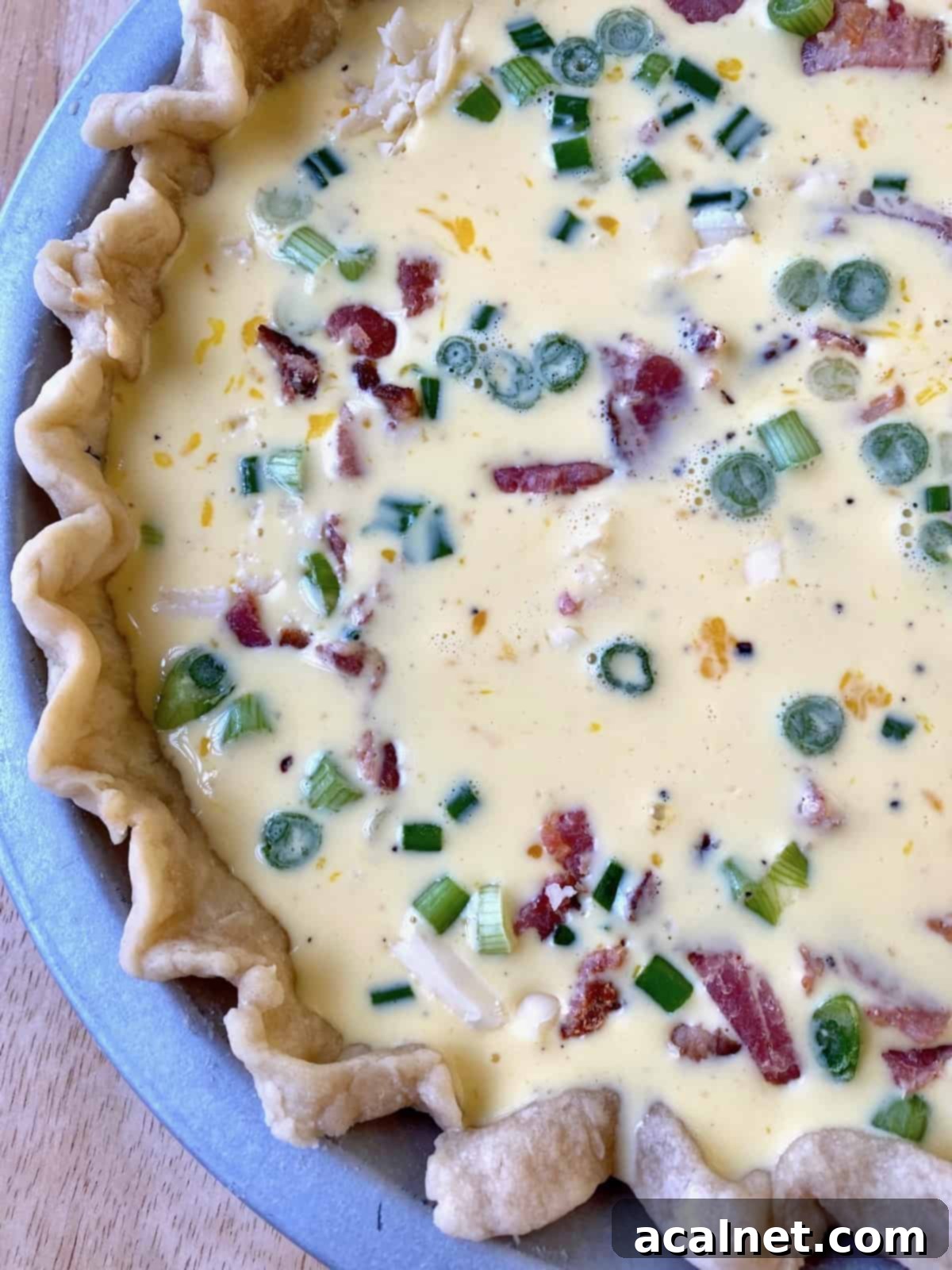 Unbaked quiche filling with bacon and diced green onions in a pie crust, before the final topping.