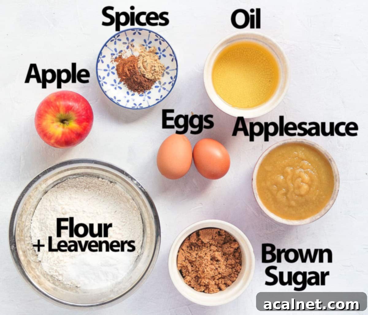 Ingredients for spiced apple loaf cake laid out on a white surface.