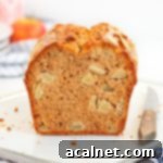 Crumb Shot of the loaf sliced in half, showing moist texture and apple chunks