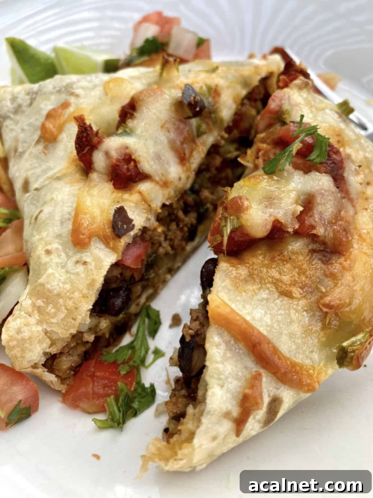 A large baked burrito cut in half, with a little salsa and cilantro.