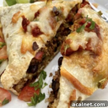 A large baked burrito cut in half, with a little salsa and cilantro.