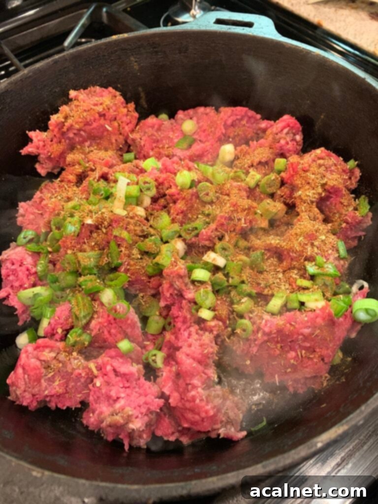 Ground beef and green onions in a skillet. 