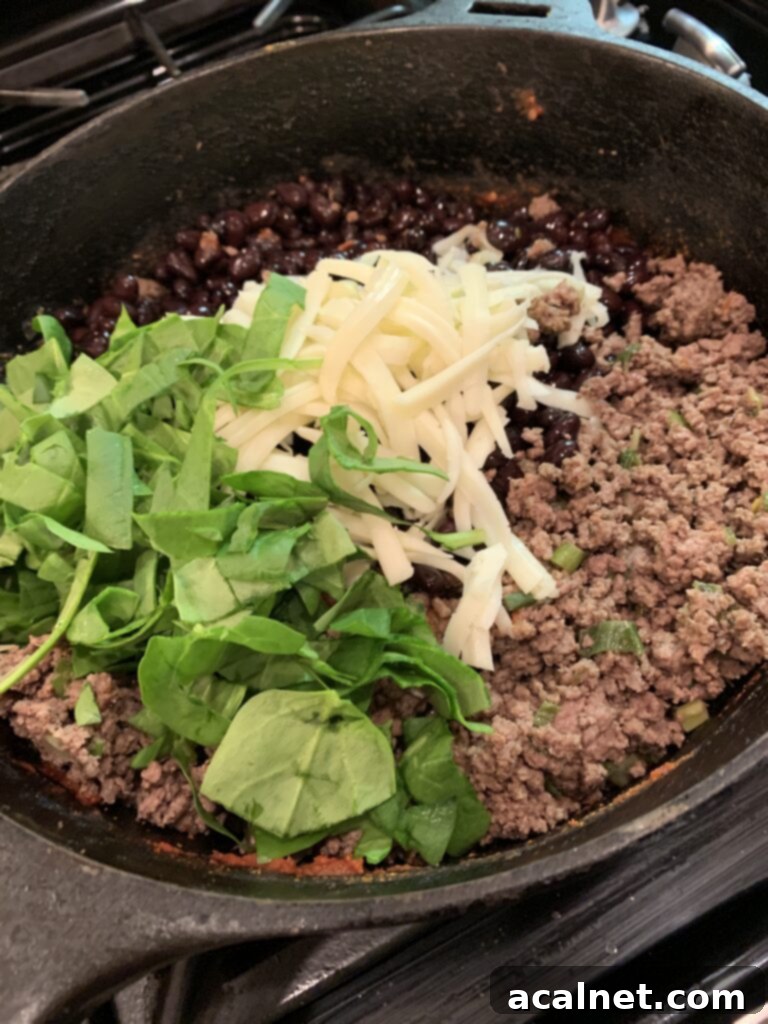 All the ingredients for beef baked burrito filling arranged in a skillet.