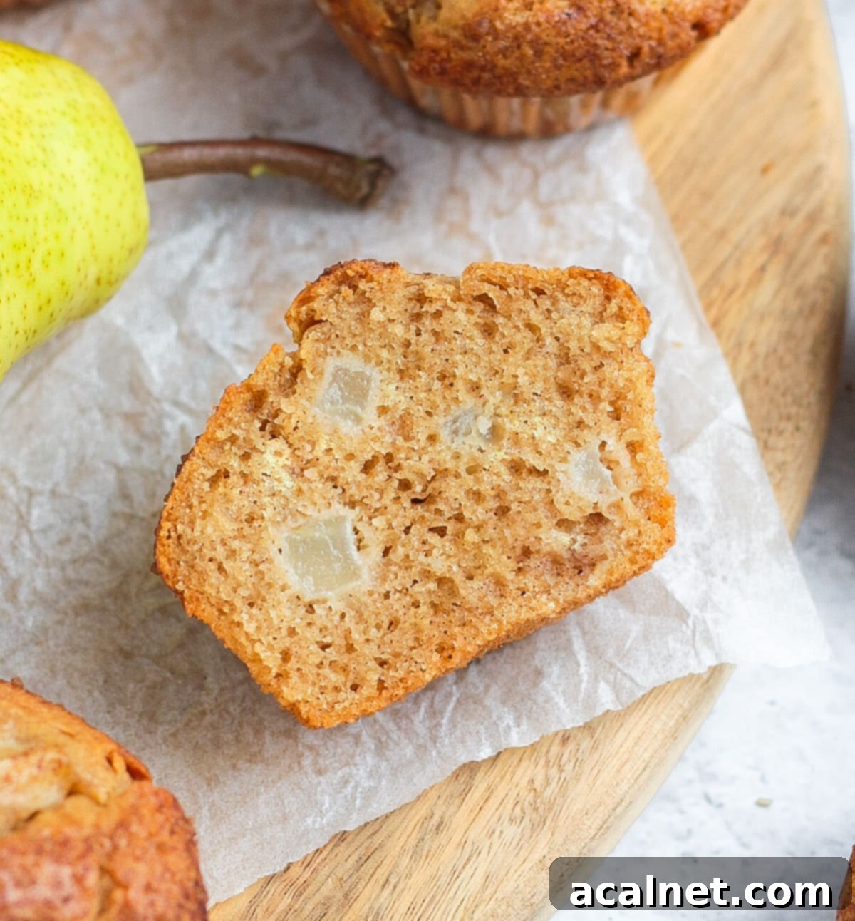 Warm Spiced Pear Muffins 8 A spiced pear muffin sliced in half, showing the moist, airy crumb and visible pear chunks inside.