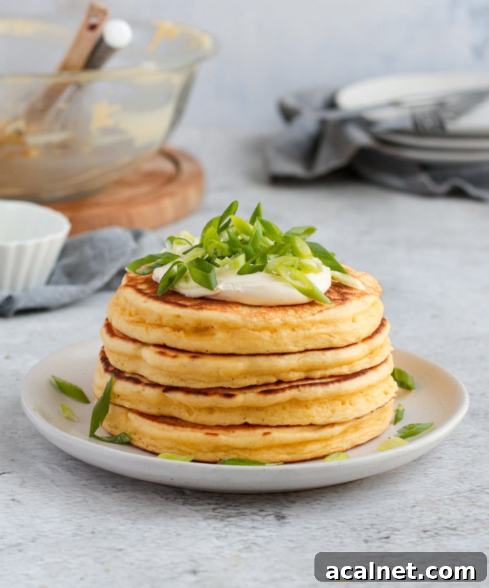 A beautifully presented stack of savory cheese pancakes on a white plate, ready to be served