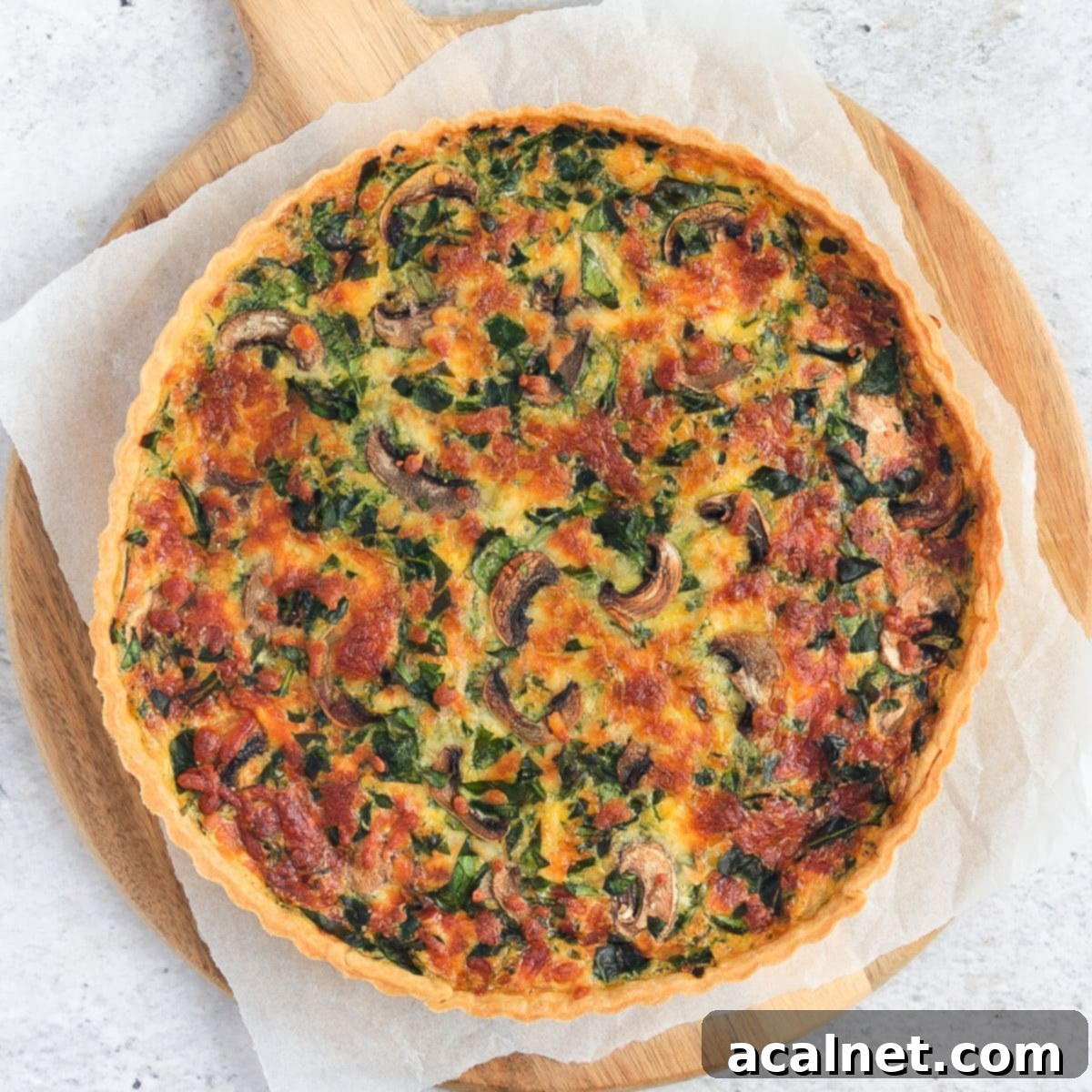 Flatlay of the quiche over white baking paper on a round wooden board