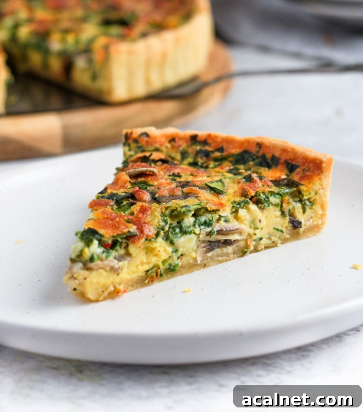 One slice of quiche on a white plate