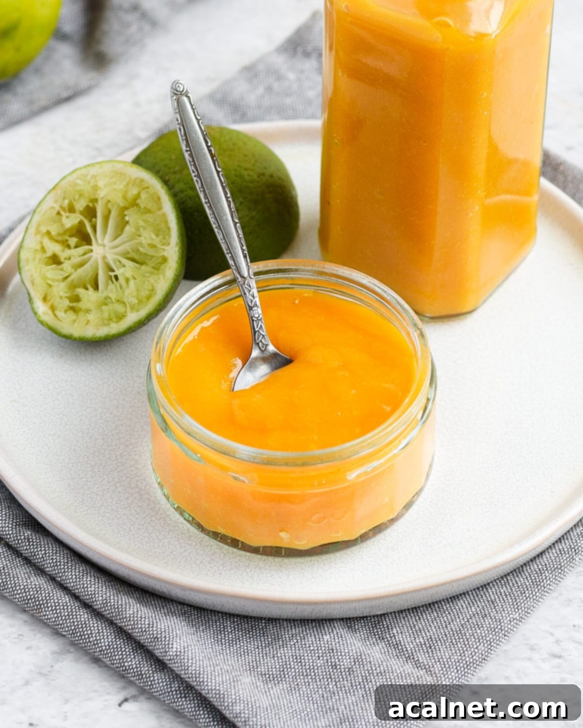 Mango coulis on a glass cup with a silver spoon