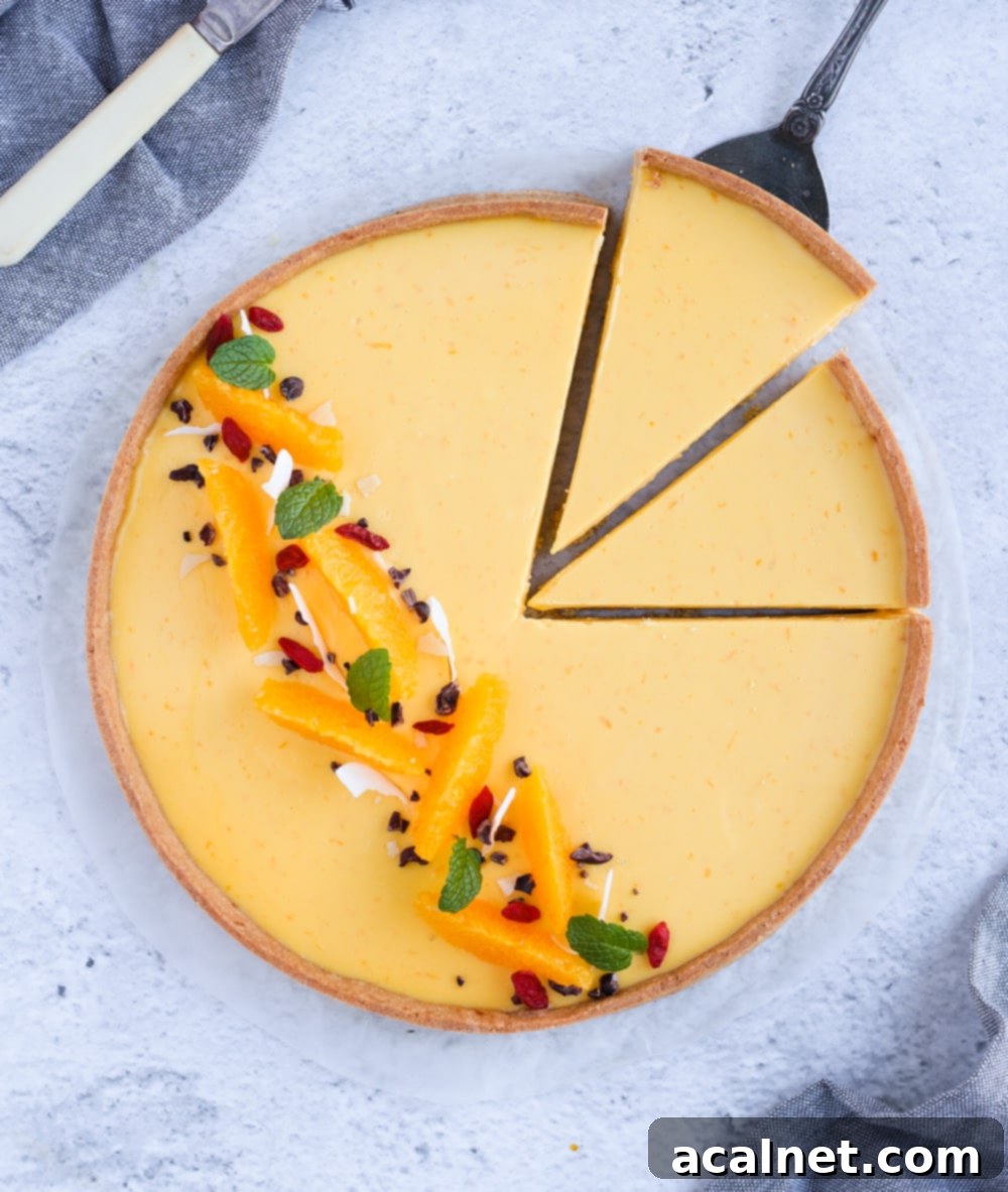 An aerial view of a beautifully baked French Orange Tart with two slices already removed, revealing the creamy orange filling.