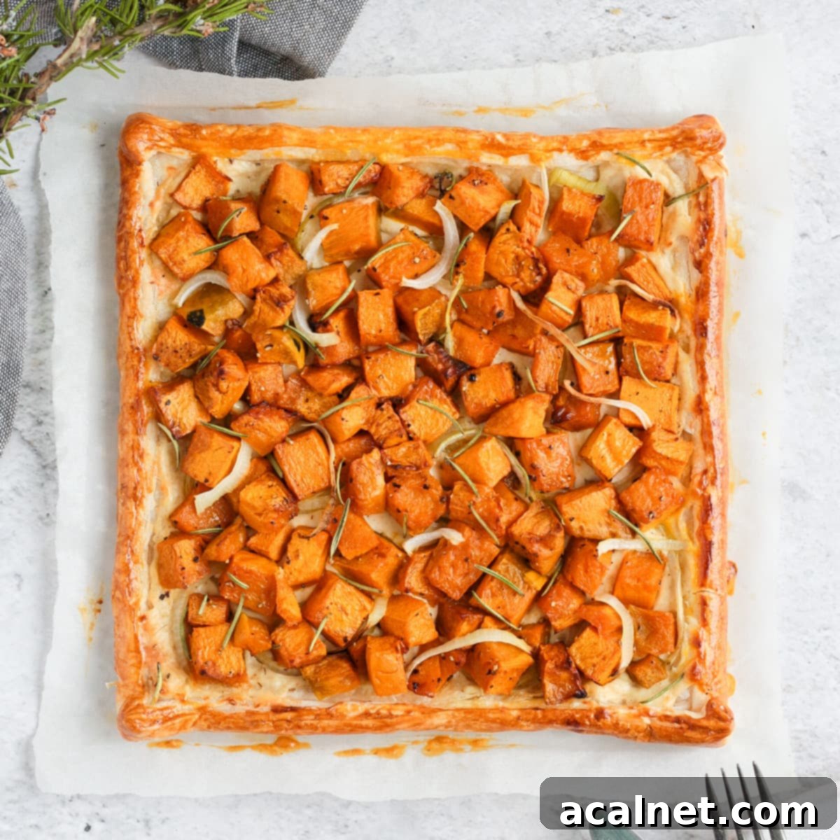 Savory Pumpkin Tart with Ricotta, Onion, and Rosemary on baking paper, viewed from above