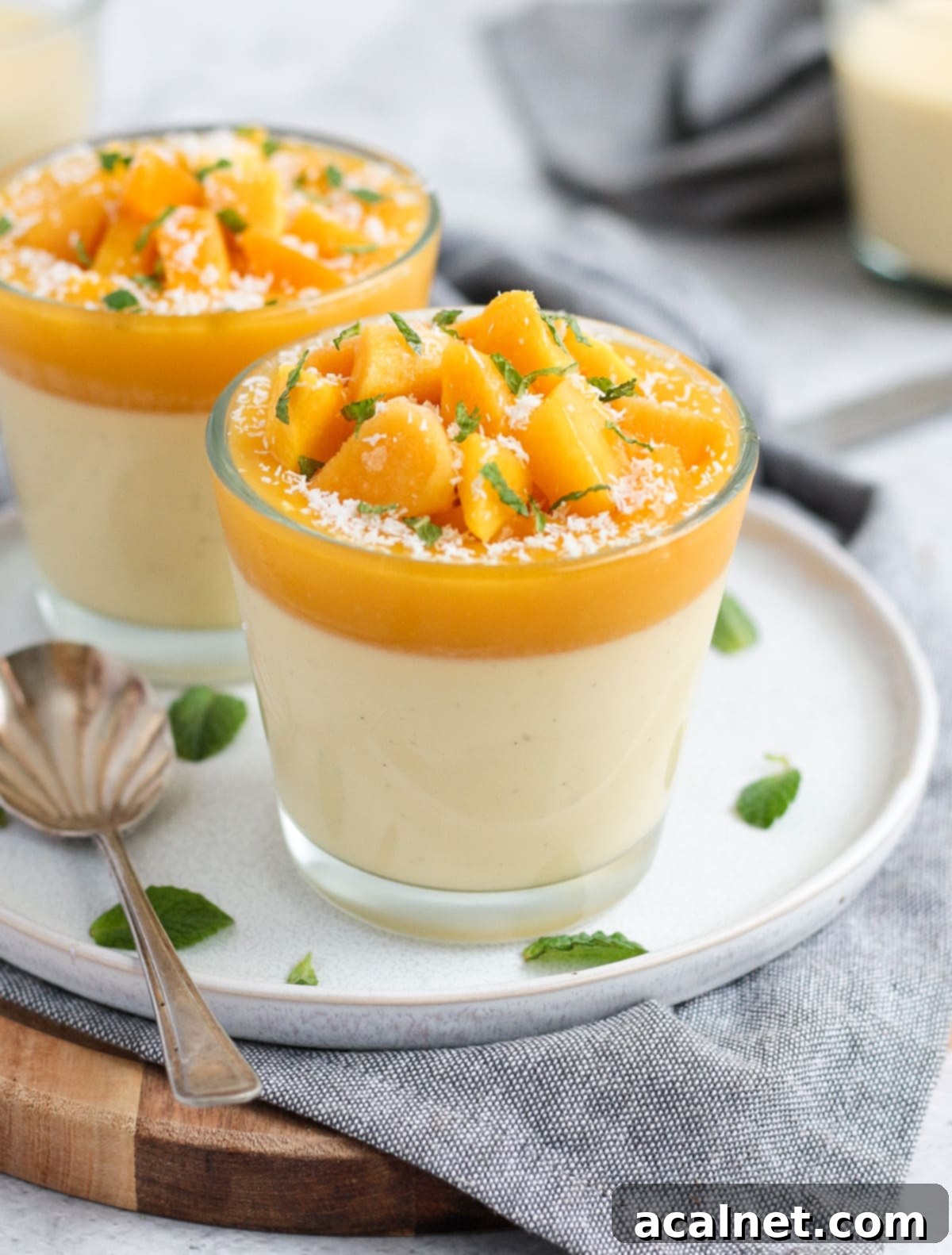 Two cups of panna cotta on a white plate over a grey napkin, ready to be served
