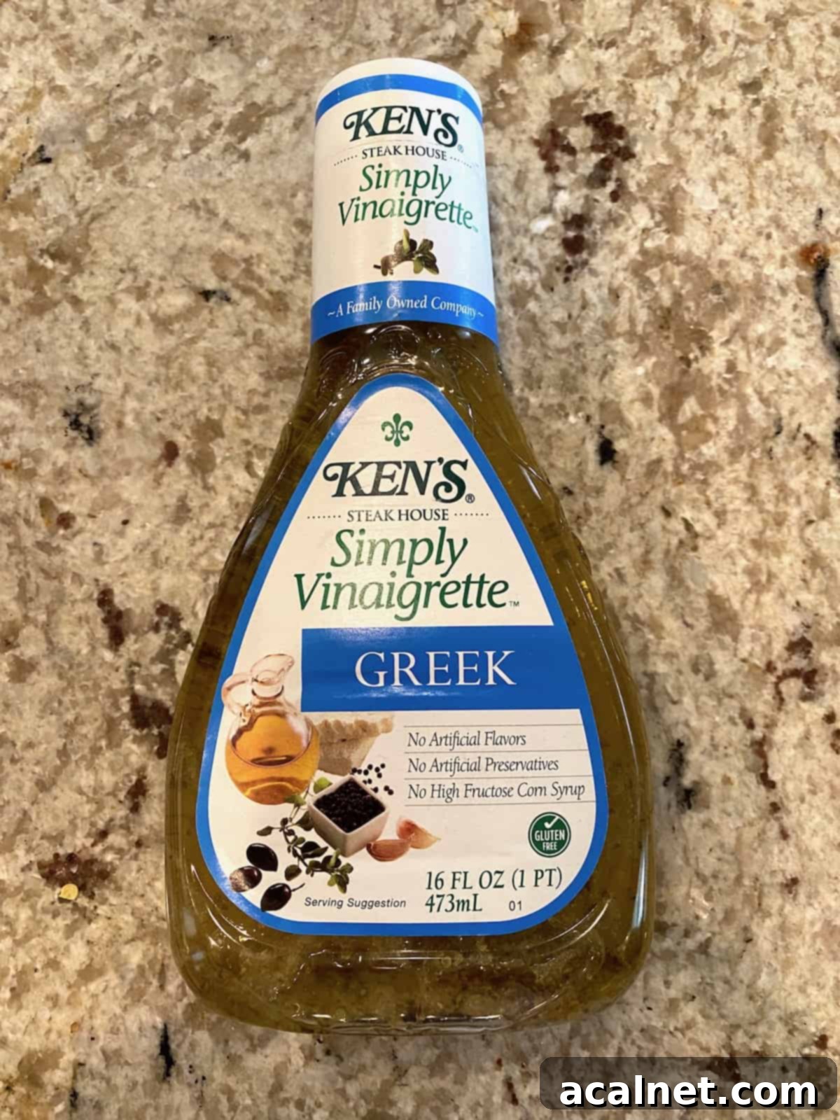 A bottle of Greek vinaigrette salad dressing stands upright, illustrating a preferred choice for the edamame salad.
