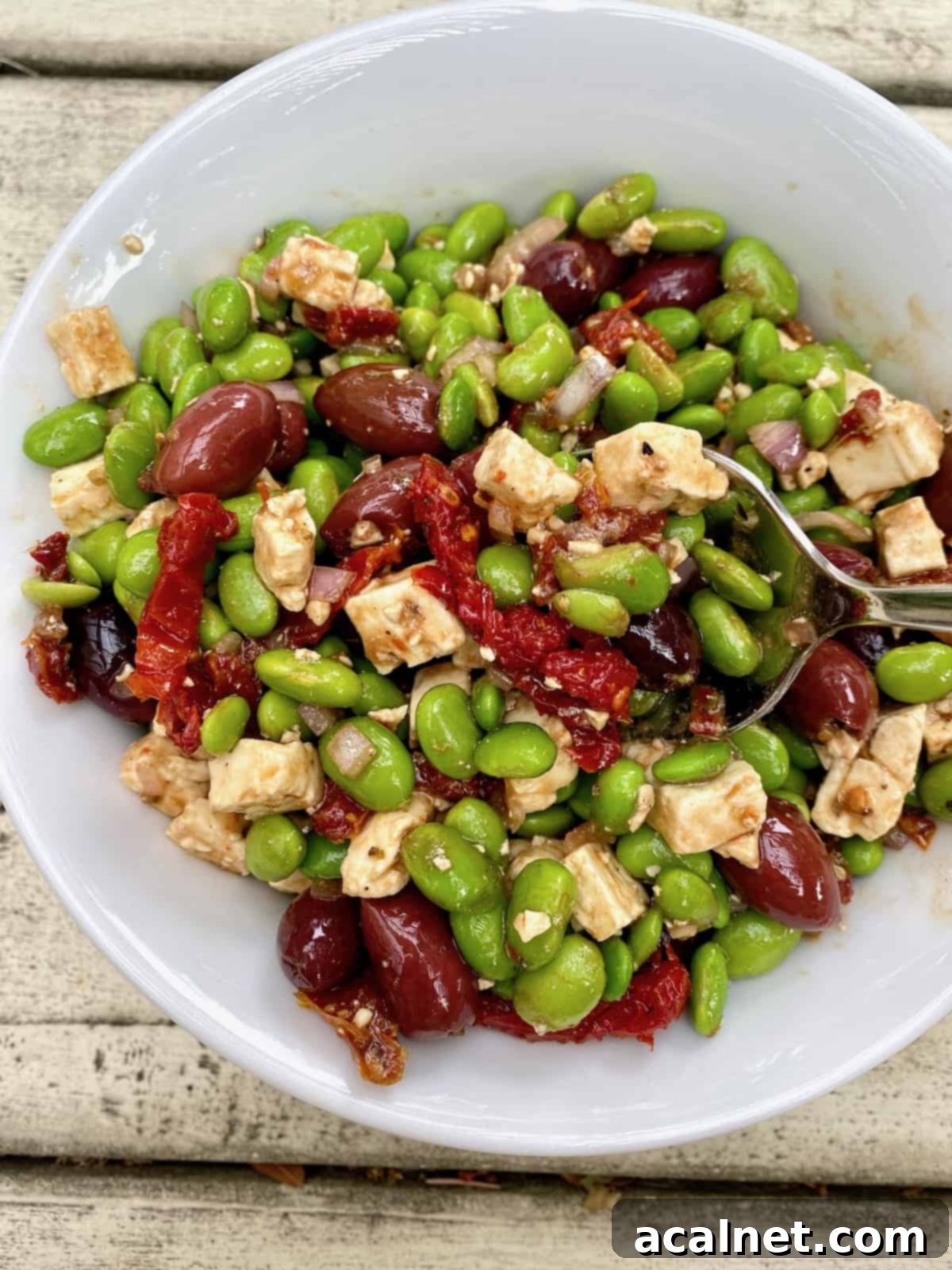 A serving of Mediterranean Edamame Salad, prepared with a balsamic vinaigrette, showing a slight darkening of the feta cheese.