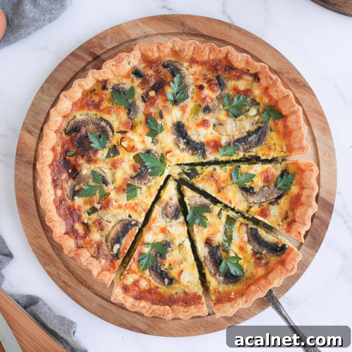 Flatlay photo of the quiche on a round board with 3 slices cut off, showcasing its golden crust and delicious filling.